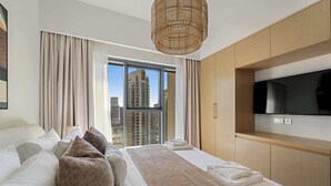 A modern hotel room with a large bed, a television mounted on the wall, and a view of tall buildings through the window. - Silkhaus Luxurious 1BR Downtown Burj Royale (Dubai)