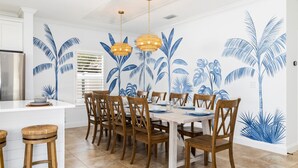 Un espace repas avec un îlot central blanc, des chaises en bois et une table dressée pour six personnes.