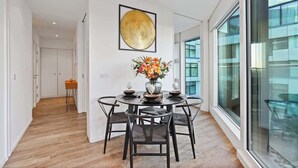 A modern dining area with a round table, chairs, and a vase of flowers. - Luxury Cube Penthouse 2BR 2BA, City Center (Birmingham)