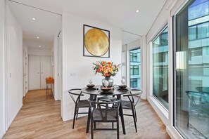 A modern dining area with a round table, chairs, and a vase of flowers. - Luxury Cube Penthouse 2BR 2BA, City Center (Birmingham)