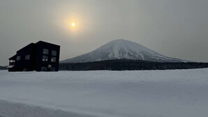 A modern building with a flat roof and large windows, situated in a snowy landscape with a snow-covered mountain in the background. - 【Yotei Mountain View】MOUNTAIN VILLA Niseko (Abuta District)