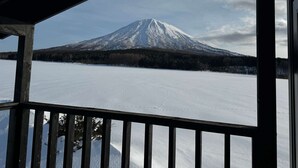 A snow-covered mountain viewed from a covered balcony with a wooden railing. - 【Yotei Mountain View】MOUNTAIN VILLA Niseko (Abuta District)