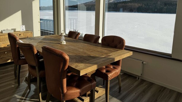 A dining area with a wooden table and leather chairs, large windows with a mountain view, and a radiator on the wall. - 【Yotei Mountain View】MOUNTAIN VILLA Niseko (Abuta District)