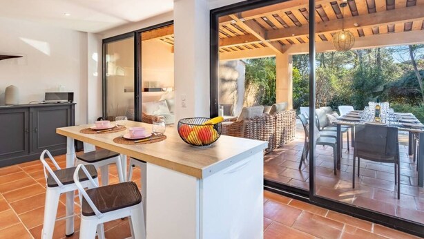 An open-plan kitchen and dining area with a large sliding glass door leading to an outdoor patio. - Villa with pool in Gassin (Gassin)