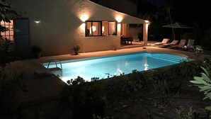 A swimming pool with a patio area, a covered seating area, and a building with exterior lighting. - Villa with pool in Gassin (Gassin)