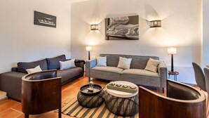 A modern living room with a grey sofa, two armchairs, and a coffee table. There are wall-mounted light fixtures and a framed picture above the sofa. - Villa with pool in Gassin (Gassin)