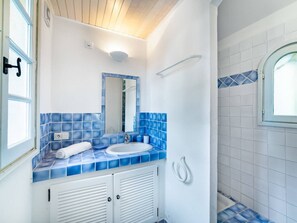 A bathroom with a white sink, blue-tiled backsplash, a mirror, and a shower area with a window. - Villa with a Pool in Gassin   (Gassin)