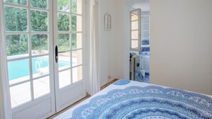 A bedroom with a large window, a bed with a patterned bedspread, and a view of a swimming pool. - Villa with pool in Gassin (Gassin)