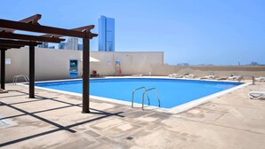 Ein Pool auf dem Dach mit freiem Blick auf ein hohes Gebäude im Hintergrund.