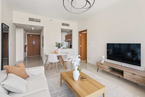 A modern living room with a sofa, coffee table, TV, and dining area. - Silkhaus 2bdr in Julphar Tower Near Reem Park (Abu Dhabi)