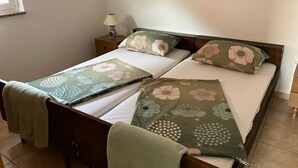 A neatly made bed with floral bedding, a bedside lamp, and a small nightstand. - 2BR Apartment With Garden in Povljana (Povljana)