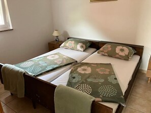 A neatly made bed with floral bedding, a bedside lamp, and a small nightstand. - 2BR Apartment With Garden in Povljana (Povljana)
