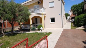A two-story building with a balcony, a small window, and a number '72' sign. - 2BR Apartment With Garden in Povljana (Povljana)