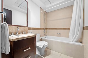 A modern bathroom with a bathtub, a toilet, a sink, and a mirror. - Silkhaus Modern Studio Emaar Tower Balcony (Dubai)