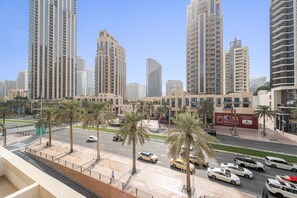 A cityscape with tall buildings, palm trees, and a busy street with cars. - Silkhaus Modern Studio Emaar Tower Balcony (Dubai)