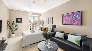 A modern hotel room with a bed, a black leather sofa, a round coffee table, and a large abstract painting on the wall. - Silkhaus Modern Studio Near Almas in West Lake (Dubai)