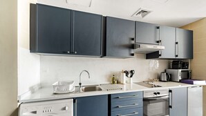 A modern kitchen with built-in appliances, a washing machine, and a compact oven. - Silkhaus Modern Studio Near Almas in West Lake (Dubai)
