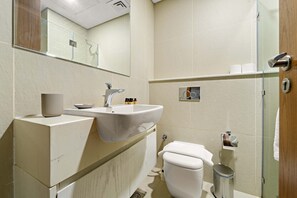 Ein modernes Badezimmer mit Waschbecken, Spiegel, Toilette und Mülleimer.