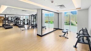 Ett gym med löpband, styrketräningsmaskiner och en vägg täckt med speglar.