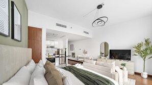 A modern hotel room with a large bed, a TV, a dining area, and a kitchen in the background. - Silkhaus Lux Studio Binghatti Pearl Near Mall (Dubai)