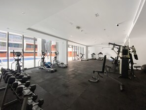 A spacious gym with treadmills, elliptical machines, and weightlifting equipment. Large windows offer views of the outside. - Silkhaus Lux Studio Binghatti Pearl Near Mall (Dubai)