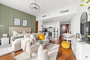 A modern hotel room with a large bed, a sofa, a dining table, and a kitchen area. - Silkhaus Lux Studio Binghatti Pearl Near Mall (Dubai)