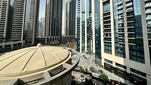 A modern high-rise building with a circular structure in the foreground, surrounded by tall residential buildings with balconies. - Silkhaus Luxury 1BR Emaar Near Burj Khalifa (Dubai)