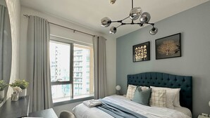 A modern bedroom with a large bed, a desk, and a window with a city view. - Silkhaus Luxury 1BR Emaar Near Burj Khalifa (Dubai)