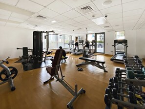 Ein Fitnessstudio mit Laufbändern, Kraftgeräten und Kurzhanteln.