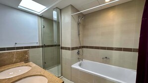 A modern bathroom with a glass-enclosed shower, a bathtub, and two sinks with marble countertops. - Silkhaus Luxury 1BR Emaar Near Burj Khalifa (Dubai)