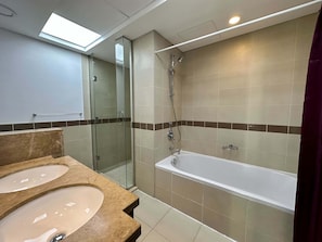 Ein modernes Badezimmer mit einer Glasdusche, einer Badewanne und zwei Waschbecken mit Marmorplatten.