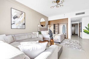 A modern living room with a sectional sofa, a coffee table, and a decorative vase. - Silkhaus Gate Tower Luxurious Studio w City View (Abu Dhabi)