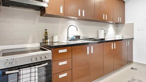 A modern kitchen with wooden cabinets, a stainless steel stove, and a black countertop. - Silkhaus Gate Tower Luxurious Studio w City View (Abu Dhabi)