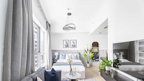 A modern bedroom with a bed, bedside tables, a TV, and a large window. - Silkhaus Dubai Marina Studio Bay Central Tower (Dubai)