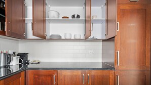 A kitchen with wooden cabinets, white tiles, and stainless steel appliances. - Silkhaus Modern 1BR 29 Blvd Heart of Downtown (Dubai)