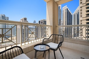 A balcony with a table and chairs, offering a view of high-rise buildings. - Silkhaus Modern 1BR 29 Blvd Heart of Downtown (Dubai)