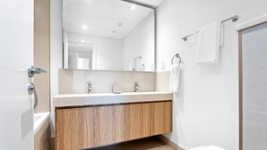 A modern bathroom with a wooden vanity, a large mirror, and a white toilet. - Silkhaus Stylish 2BR Downtown Views II Emaar (Dubai)