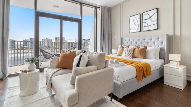 A modern hotel room with a large bed, a sofa, and a view of the cityscape. - Silkhaus New Studio Binghatti Pearl in DSO (Dubai)