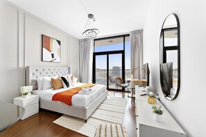 Ett modernt hotellrum med en stor säng, ett skrivbord, en stol, en TV och en balkong med utsikt över staden.