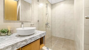 Een moderne badkamer met een groot wit wastafelmeubel, een glazen douchecabine en een houten opbergmeubel.