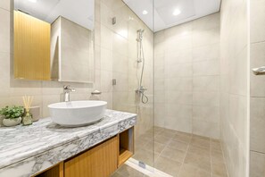 A modern bathroom with a large white sink, a glass shower enclosure, and a wooden vanity. - Silkhaus Stylish 2bdr in Aykon Tower (Dubai)