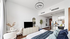 Ein modernes Hotelzimmer mit einem großen Bett, einem Fernseher, einer Essecke und einer Küchenzeile.