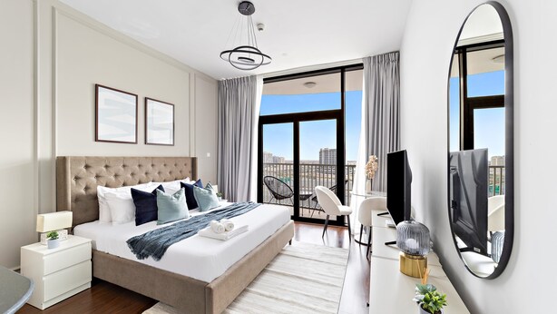 Ein modernes Hotelzimmer mit einem großen Bett, einem Schreibtisch, einem Stuhl, einem Fernseher und einem Balkon mit Blick auf die Stadt.