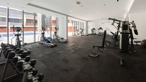 Ein geräumiges Fitnessstudio mit Laufbändern, Crosstrainern und Gewichten. Große Fenster bieten Ausblicke nach draußen.