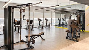 A gym with various exercise equipment, large windows, and a view of the city. - Silkhaus New Modern Studio Business Bay (Dubai)