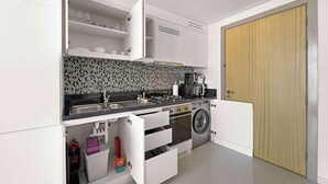 A compact kitchen with a washing machine, a microwave, and a sink. - Silkhaus New Modern Studio Business Bay (Dubai)