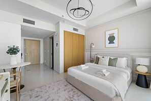 Et moderne hotelværelse med en stor seng, et sengebord, en lampe og et billede i ramme på væggen.