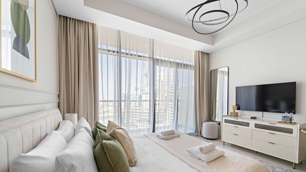 A modern hotel room with a large bed, a sofa, a TV, and a balcony with curtains. - Silkhaus New Modern Studio Business Bay (Dubai)