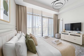 Et moderne hotelværelse med en stor seng, en sofa, et fjernsyn og en balkon med gardiner.