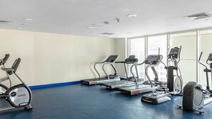A gym with treadmills, elliptical machines, and a stationary bike. - Silkhaus Cozy 1BR With Balcony Pool Gym on Reem Island (Abu Dhabi)